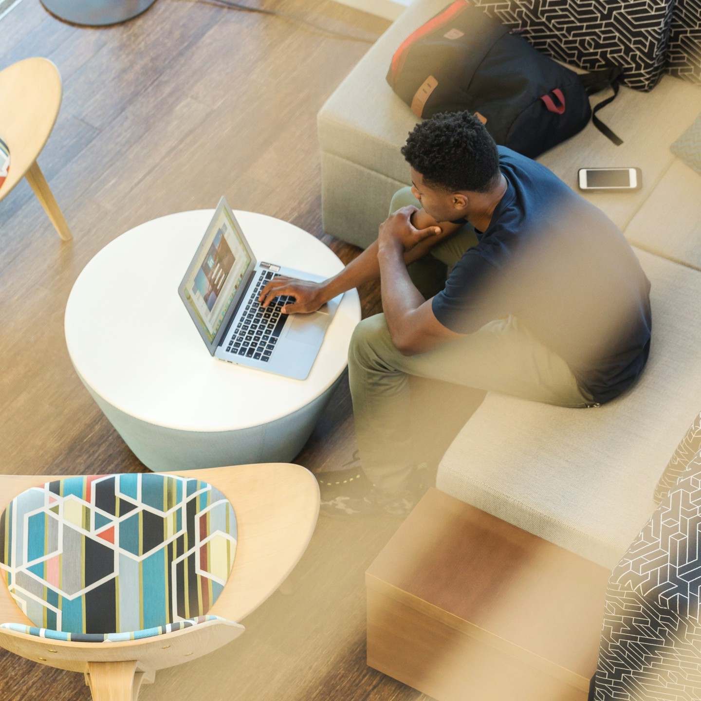 A shot through a 2nd floor interior window of a man on his laptop