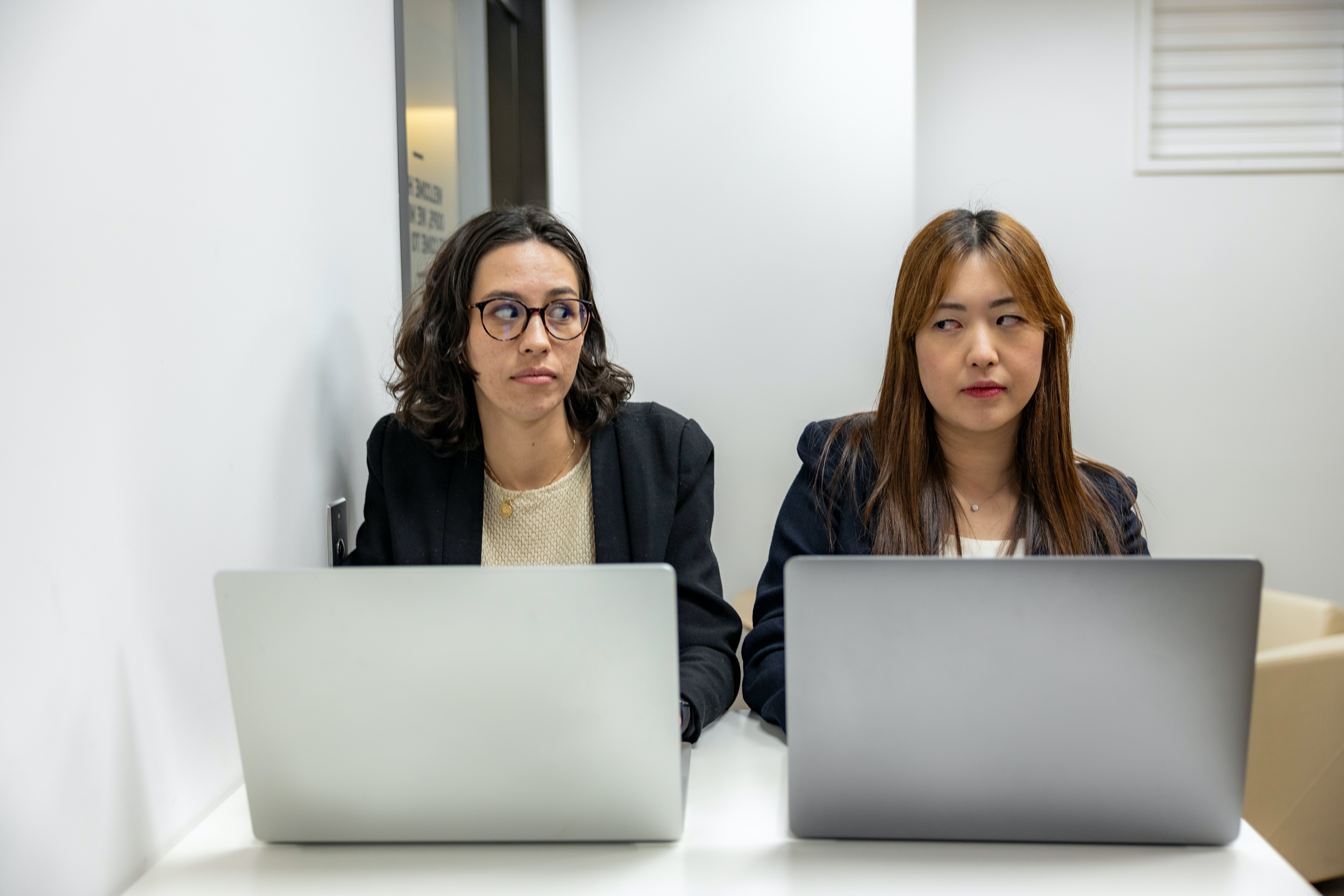 two young women working and giving eachother a knowing look