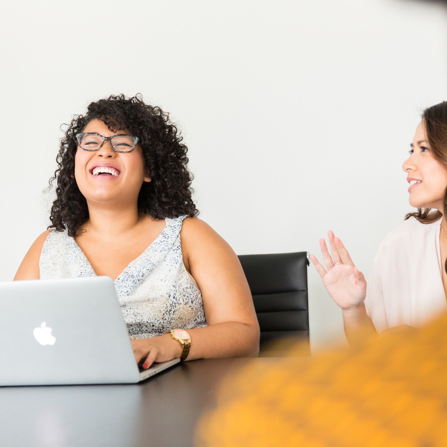 Young woman on her laptop laughing with colleagues